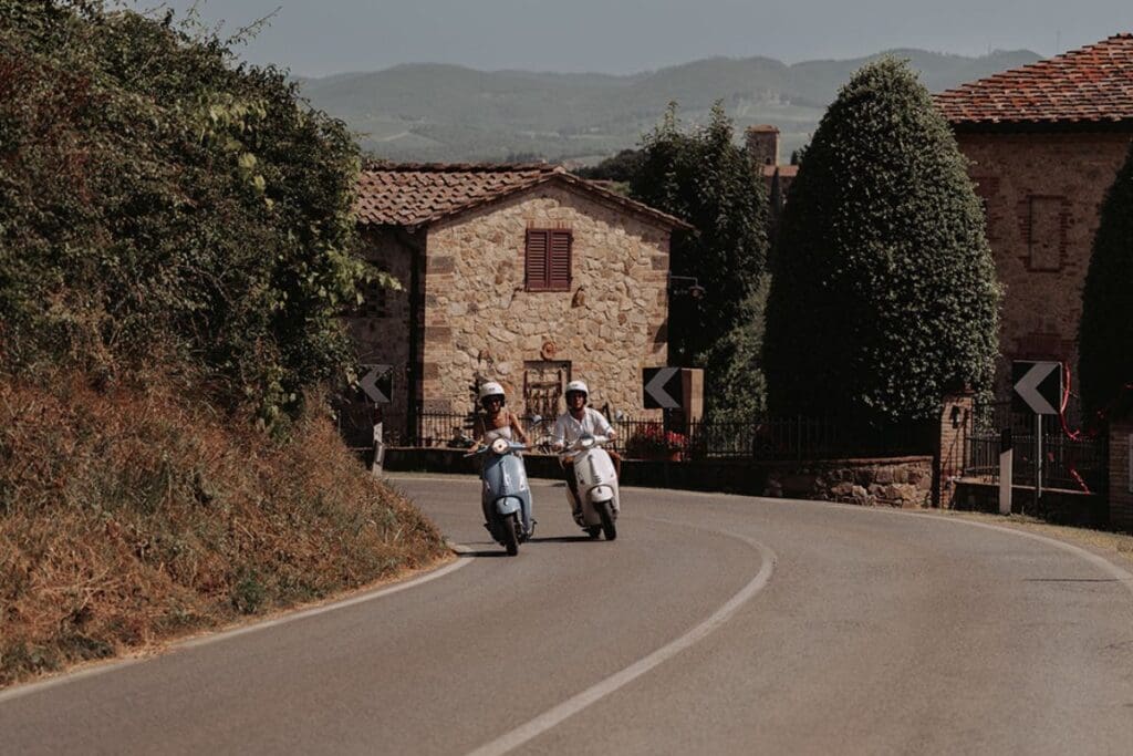 two people on two vespa's on the road